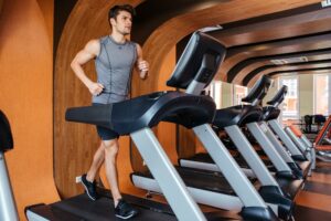 Fitness man working out and running on treadmill in gym