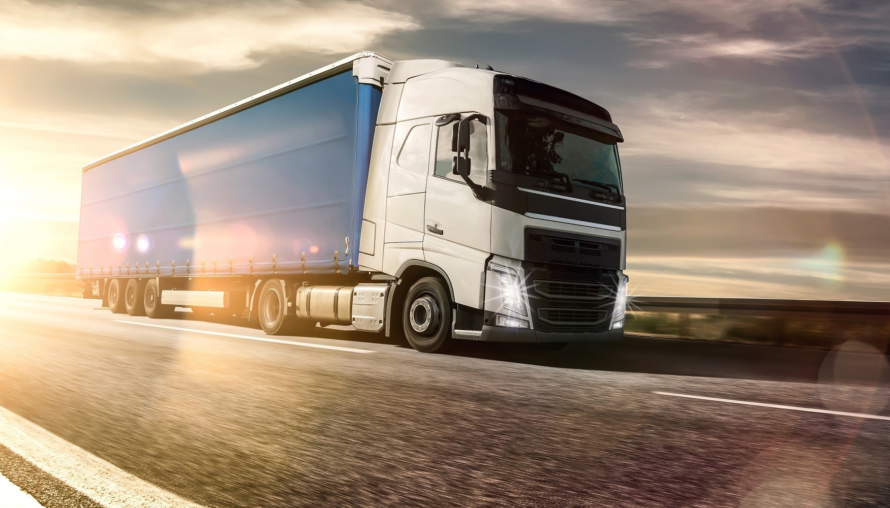 Modern HGV truck driving on a highway at sunset