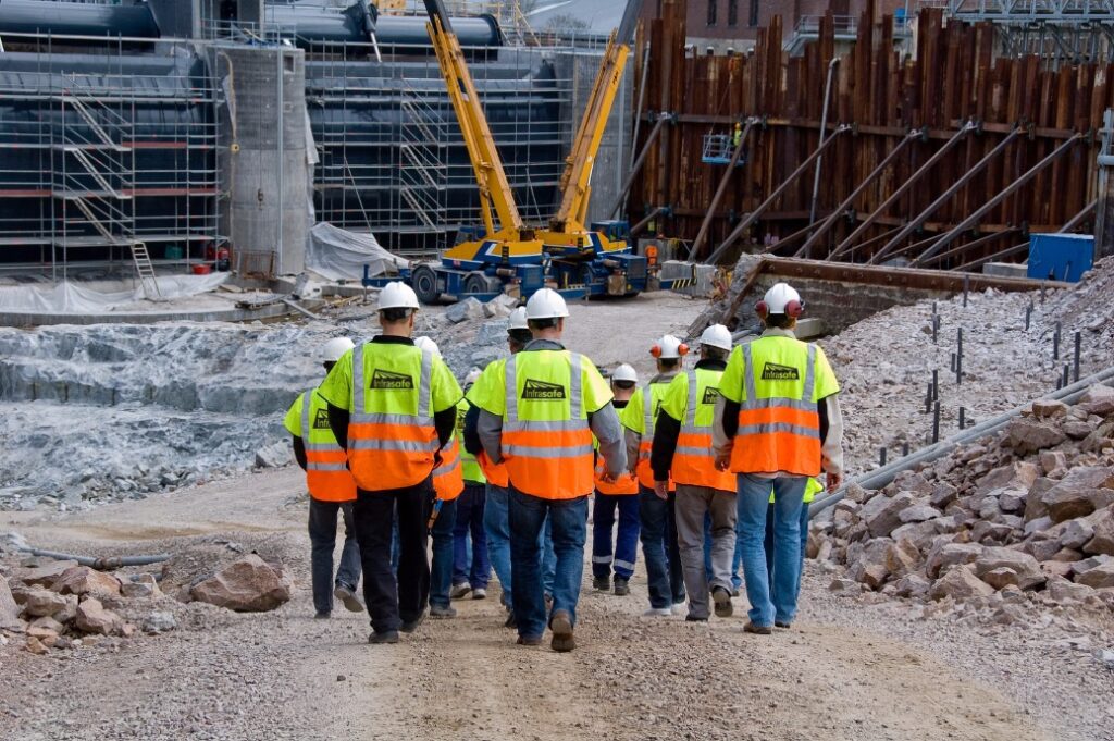 Construction workers wearing high-visibility vests and hard hats at a work site, emphasizing the importance of safety critical medicals provided by Motor Medicals for just £100.
