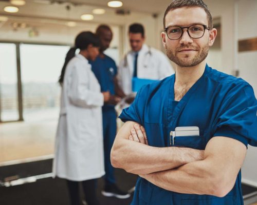 Confident relaxed surgeon doctor at hospital with team of doctors in background